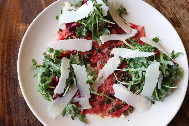 Thinly sliced raw wagyu beef under arugula and shavings of parmigiano reggiano
