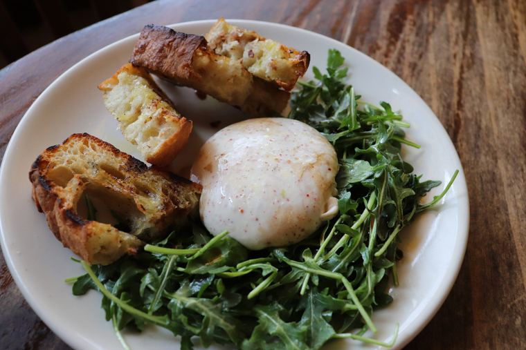 Burrata with grilled ciabatta and arugula on a white plate