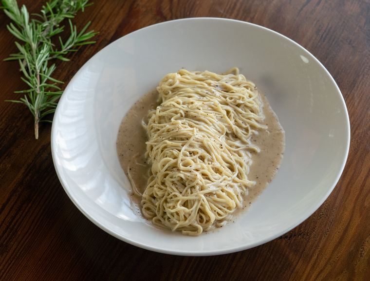 Spaghetti cacio e pepe in a shallow white bowl