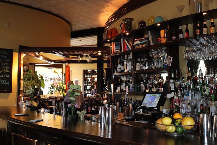The Vespaio bar with bottles shelved to the ceiling and a bowl of lemons on the counter