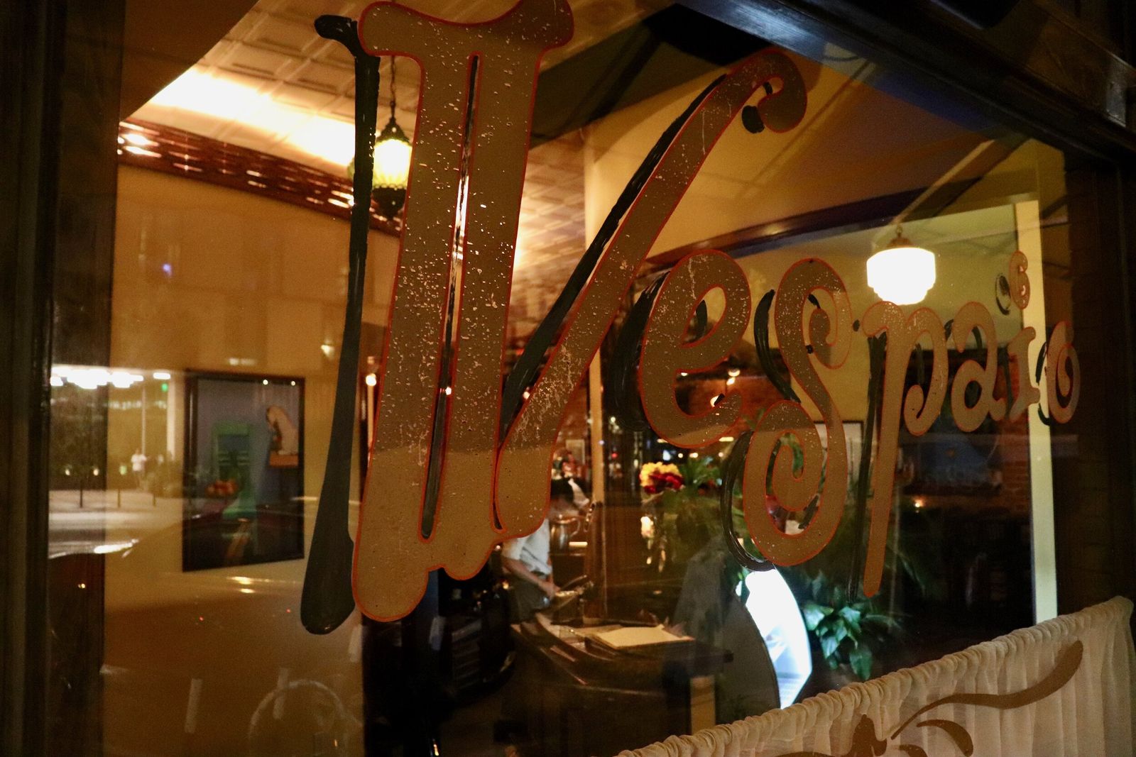 The Vespaio script logo painted on a window and lit from inside at night