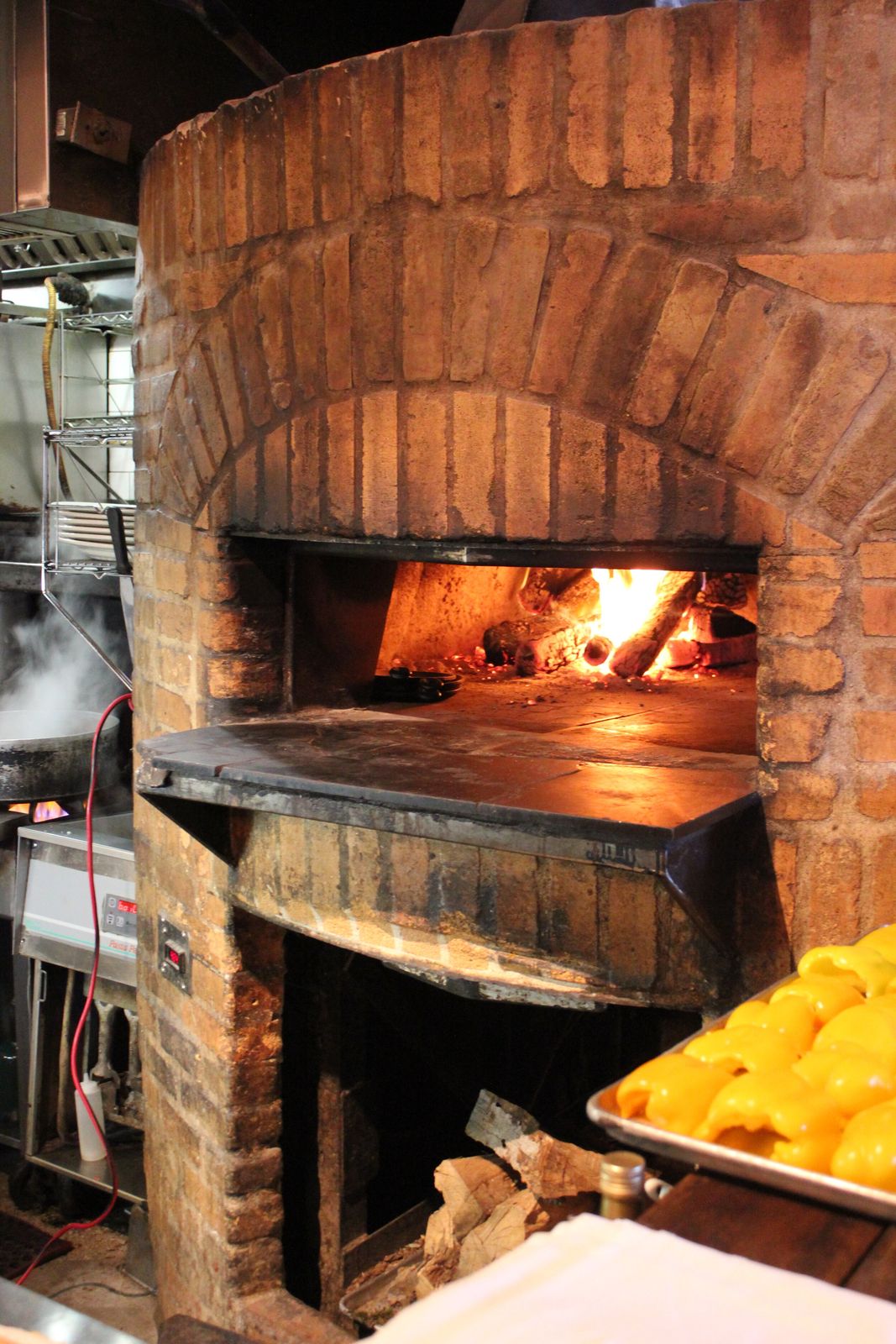 The mouth of a wood-fired brick oven with flames burning inside